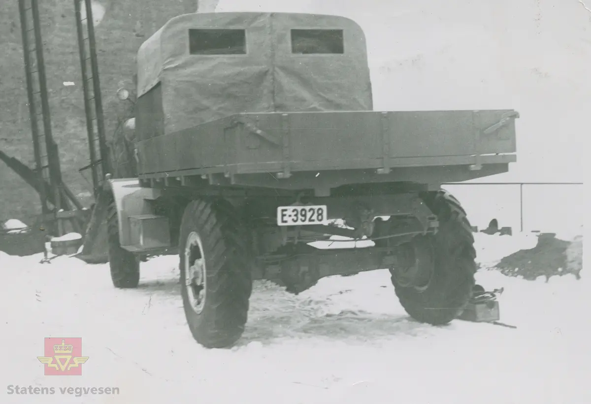 Tekst på bildet "Filefjell-Gubben". FWD lastebil modell SU fra A/S Jotunheimen og Valdresruten Bilselskap (JVB) med kjennetegn E-3928. Bilen ble levert til Jotunheimen, Valdresruten i 1936, og holdt vegen over Filefjell åpen. Klikk på pilen til høyre for å se tilleggsbilder: Legg merke til benkene på lasteplanet med tak og presenning til ly for vær og vind for brøytemannskap.   
Etter en tøff vinter 1936-1937 mottok Colbjørnsen brev fra JVB, A/S Jotunheimen og Valdresruten Bilselskap  30.04.1937, hvor de sier seg meget fornøyd med bilen de kjøpte før jul i 1936. Jf. boka "Familiefirmaet-utenom allfarvei/2000 Årsboken."Colbjørnsen & Co A/S, av Bjørn Ausjen Johannessen. Bilde av "Filefjell-Gubben" i A/S Jotunheimen og Valdresruten Bilselskap  på en av veivesenets garasjer på Filefjell vises i tilleggbildene.  FWD lastebilen "Filefjell-Gubben" ble innkjøpt av JVB  i 1936. Den til da kraftigste i landet. Vegfolk kom da også fra fjern og nær for å bivåne brøytingen, og for å se og lære. 
 "A/S Jotunheimen og Valdresruten Bilselskap  ble etablert i 1919 og har vært selve livsnerven gjennom Valdresbygdene. "Filefjell-Gubben" ble satt inn i arbeidet med å holde Filefjellvegen oppe. Med felles innsats og arbeid fra Staten og selskapets side, lykkes det å holde Filefjellvegen farbar for vintertrafikk vinteren 1936-1937, den første fjellovergang i Norge som var åpen året rundt." Jf. Kilde: "JVB. Den spede begynnelse-A/S Jotunheimen og Valdresruten Bilselskap."  
Personene på bildet er ukjente. Bildene som vises er både fra Oslo og Filefjell. 
Bildene er registrert enkeltvis på nr: 
Bilde 2) NVM 00-F-33671
Bilde 3  NVM 00-F-33672
Bilde 4  NVM 00-F-33704
Bilde 5) NVM 00-F-33705
Bilde 6) NVM 00-F-33707
Bilde 7) NVM 00-F-33708
Bilde 8) NVM 00-F-33710
Bilde 9) NVM 00-F-33711
Bilde 10)NVM 00-F33659
Bilde 11)NVM 00-F33660