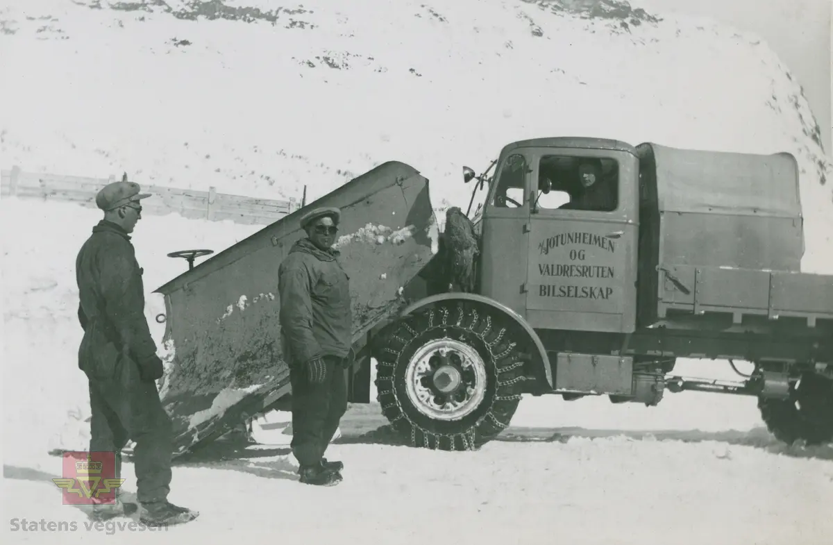 Tekst på bildet "Filefjell-Gubben". FWD lastebil modell SU fra A/S Jotunheimen og Valdresruten Bilselskap (JVB) med kjennetegn E-3928. Bilen ble levert til Jotunheimen, Valdresruten i 1936, og holdt vegen over Filefjell åpen. Klikk på pilen til høyre for å se tilleggsbilder: Legg merke til benkene på lasteplanet med tak og presenning til ly for vær og vind for brøytemannskap.   
Etter en tøff vinter 1936-1937 mottok Colbjørnsen brev fra JVB, A/S Jotunheimen og Valdresruten Bilselskap  30.04.1937, hvor de sier seg meget fornøyd med bilen de kjøpte før jul i 1936. Jf. boka "Familiefirmaet-utenom allfarvei/2000 Årsboken."Colbjørnsen & Co A/S, av Bjørn Ausjen Johannessen. Bilde av "Filefjell-Gubben" i A/S Jotunheimen og Valdresruten Bilselskap  på en av veivesenets garasjer på Filefjell vises i tilleggbildene.  FWD lastebilen "Filefjell-Gubben" ble innkjøpt av JVB  i 1936. Den til da kraftigste i landet. Vegfolk kom da også fra fjern og nær for å bivåne brøytingen, og for å se og lære. 
 "A/S Jotunheimen og Valdresruten Bilselskap  ble etablert i 1919 og har vært selve livsnerven gjennom Valdresbygdene. "Filefjell-Gubben" ble satt inn i arbeidet med å holde Filefjellvegen oppe. Med felles innsats og arbeid fra Staten og selskapets side, lykkes det å holde Filefjellvegen farbar for vintertrafikk vinteren 1936-1937, den første fjellovergang i Norge som var åpen året rundt." Jf. Kilde: "JVB. Den spede begynnelse-A/S Jotunheimen og Valdresruten Bilselskap."  
Personene på bildet er ukjente. Bildene som vises er både fra Oslo og Filefjell. 
Bildene er registrert enkeltvis på nr: 
Bilde 2) NVM 00-F-33671
Bilde 3  NVM 00-F-33672
Bilde 4  NVM 00-F-33704
Bilde 5) NVM 00-F-33705
Bilde 6) NVM 00-F-33707
Bilde 7) NVM 00-F-33708
Bilde 8) NVM 00-F-33710
Bilde 9) NVM 00-F-33711
Bilde 10)NVM 00-F33659
Bilde 11)NVM 00-F33660