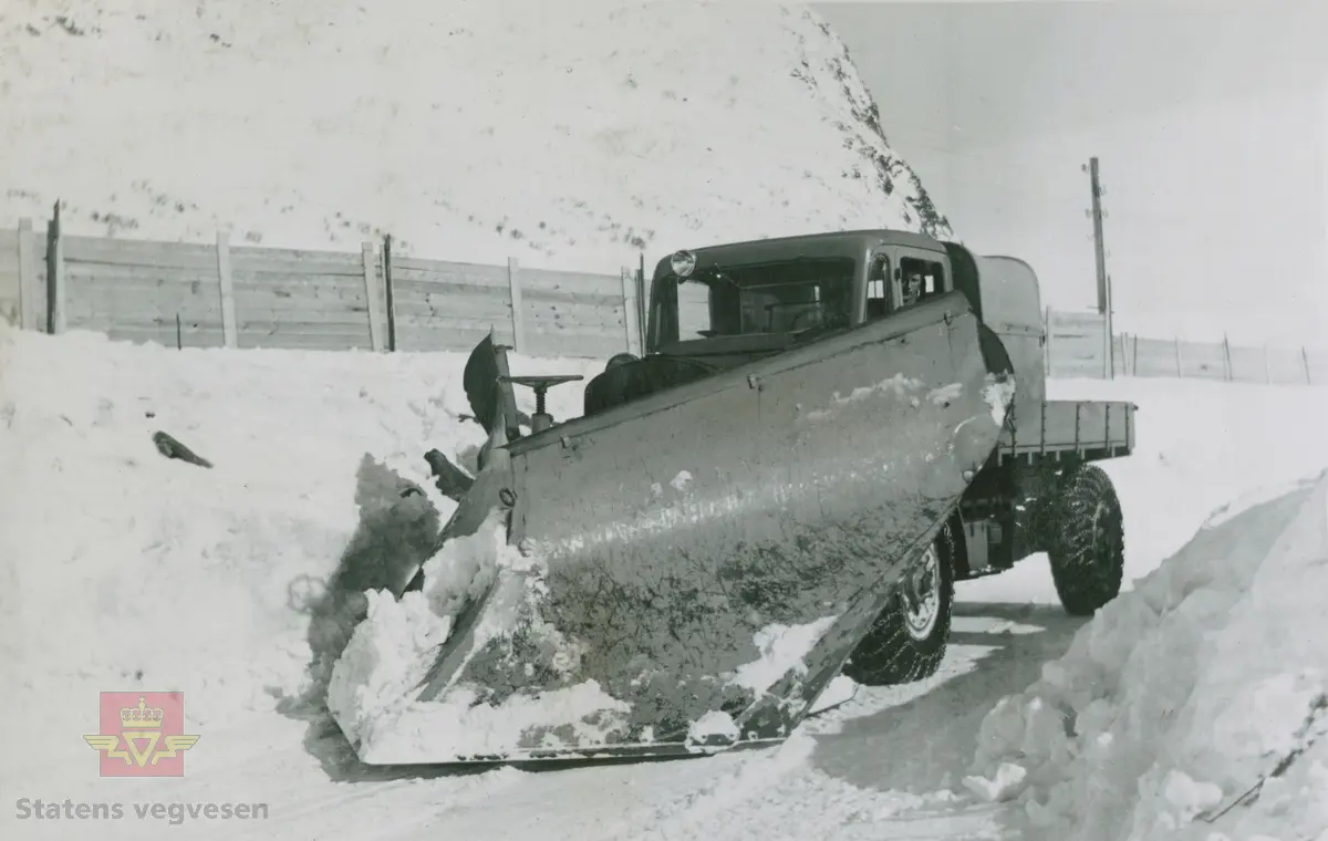Tekst på bildet "Filefjell-Gubben". FWD lastebil modell SU fra A/S Jotunheimen og Valdresruten Bilselskap (JVB) med kjennetegn E-3928. Bilen ble levert til Jotunheimen, Valdresruten i 1936, og holdt vegen over Filefjell åpen. Klikk på pilen til høyre for å se tilleggsbilder: Legg merke til benkene på lasteplanet med tak og presenning til ly for vær og vind for brøytemannskap.   
Etter en tøff vinter 1936-1937 mottok Colbjørnsen brev fra JVB, A/S Jotunheimen og Valdresruten Bilselskap  30.04.1937, hvor de sier seg meget fornøyd med bilen de kjøpte før jul i 1936. Jf. boka "Familiefirmaet-utenom allfarvei/2000 Årsboken."Colbjørnsen & Co A/S, av Bjørn Ausjen Johannessen. Bilde av "Filefjell-Gubben" i A/S Jotunheimen og Valdresruten Bilselskap  på en av veivesenets garasjer på Filefjell vises i tilleggbildene.  FWD lastebilen "Filefjell-Gubben" ble innkjøpt av JVB  i 1936. Den til da kraftigste i landet. Vegfolk kom da også fra fjern og nær for å bivåne brøytingen, og for å se og lære. 
 "A/S Jotunheimen og Valdresruten Bilselskap  ble etablert i 1919 og har vært selve livsnerven gjennom Valdresbygdene. "Filefjell-Gubben" ble satt inn i arbeidet med å holde Filefjellvegen oppe. Med felles innsats og arbeid fra Staten og selskapets side, lykkes det å holde Filefjellvegen farbar for vintertrafikk vinteren 1936-1937, den første fjellovergang i Norge som var åpen året rundt." Jf. Kilde: "JVB. Den spede begynnelse-A/S Jotunheimen og Valdresruten Bilselskap."  
Personene på bildet er ukjente. Bildene som vises er både fra Oslo og Filefjell. 
Bildene er registrert enkeltvis på nr: 
Bilde 2) NVM 00-F-33671
Bilde 3  NVM 00-F-33672
Bilde 4  NVM 00-F-33704
Bilde 5) NVM 00-F-33705
Bilde 6) NVM 00-F-33707
Bilde 7) NVM 00-F-33708
Bilde 8) NVM 00-F-33710
Bilde 9) NVM 00-F-33711
Bilde 10)NVM 00-F33659
Bilde 11)NVM 00-F33660