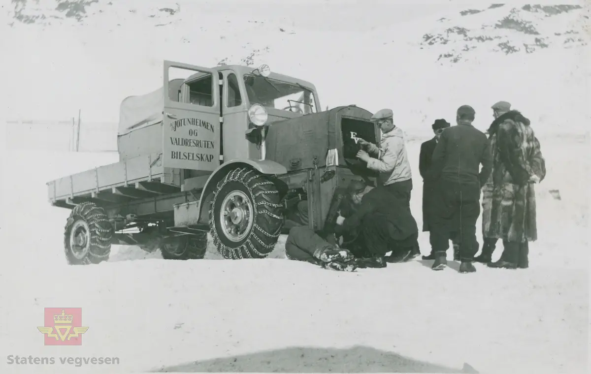 Tekst på bildet "Filefjell-Gubben". FWD lastebil modell SU fra A/S Jotunheimen og Valdresruten Bilselskap (JVB) med kjennetegn E-3928. Bilen ble levert til Jotunheimen, Valdresruten i 1936, og holdt vegen over Filefjell åpen. Klikk på pilen til høyre for å se tilleggsbilder: Legg merke til benkene på lasteplanet med tak og presenning til ly for vær og vind for brøytemannskap.   
Etter en tøff vinter 1936-1937 mottok Colbjørnsen brev fra JVB, A/S Jotunheimen og Valdresruten Bilselskap  30.04.1937, hvor de sier seg meget fornøyd med bilen de kjøpte før jul i 1936. Jf. boka "Familiefirmaet-utenom allfarvei/2000 Årsboken."Colbjørnsen & Co A/S, av Bjørn Ausjen Johannessen. Bilde av "Filefjell-Gubben" i A/S Jotunheimen og Valdresruten Bilselskap  på en av veivesenets garasjer på Filefjell vises i tilleggbildene.  FWD lastebilen "Filefjell-Gubben" ble innkjøpt av JVB  i 1936. Den til da kraftigste i landet. Vegfolk kom da også fra fjern og nær for å bivåne brøytingen, og for å se og lære. 
 "A/S Jotunheimen og Valdresruten Bilselskap  ble etablert i 1919 og har vært selve livsnerven gjennom Valdresbygdene. "Filefjell-Gubben" ble satt inn i arbeidet med å holde Filefjellvegen oppe. Med felles innsats og arbeid fra Staten og selskapets side, lykkes det å holde Filefjellvegen farbar for vintertrafikk vinteren 1936-1937, den første fjellovergang i Norge som var åpen året rundt." Jf. Kilde: "JVB. Den spede begynnelse-A/S Jotunheimen og Valdresruten Bilselskap."  
Personene på bildet er ukjente. Bildene som vises er både fra Oslo og Filefjell. 
Bildene er registrert enkeltvis på nr: 
Bilde 2) NVM 00-F-33671
Bilde 3  NVM 00-F-33672
Bilde 4  NVM 00-F-33704
Bilde 5) NVM 00-F-33705
Bilde 6) NVM 00-F-33707
Bilde 7) NVM 00-F-33708
Bilde 8) NVM 00-F-33710
Bilde 9) NVM 00-F-33711
Bilde 10)NVM 00-F33659
Bilde 11)NVM 00-F33660