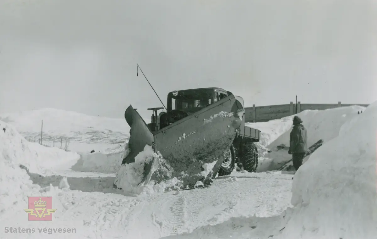 Tekst på bildet "Filefjell-Gubben". FWD lastebil modell SU fra A/S Jotunheimen og Valdresruten Bilselskap (JVB) med kjennetegn E-3928. Bilen ble levert til Jotunheimen, Valdresruten i 1936, og holdt vegen over Filefjell åpen. Klikk på pilen til høyre for å se tilleggsbilder: Legg merke til benkene på lasteplanet med tak og presenning til ly for vær og vind for brøytemannskap.   
Etter en tøff vinter 1936-1937 mottok Colbjørnsen brev fra JVB, A/S Jotunheimen og Valdresruten Bilselskap  30.04.1937, hvor de sier seg meget fornøyd med bilen de kjøpte før jul i 1936. Jf. boka "Familiefirmaet-utenom allfarvei/2000 Årsboken."Colbjørnsen & Co A/S, av Bjørn Ausjen Johannessen. Bilde av "Filefjell-Gubben" i A/S Jotunheimen og Valdresruten Bilselskap  på en av veivesenets garasjer på Filefjell vises i tilleggbildene.  FWD lastebilen "Filefjell-Gubben" ble innkjøpt av JVB  i 1936. Den til da kraftigste i landet. Vegfolk kom da også fra fjern og nær for å bivåne brøytingen, og for å se og lære. 
 "A/S Jotunheimen og Valdresruten Bilselskap  ble etablert i 1919 og har vært selve livsnerven gjennom Valdresbygdene. "Filefjell-Gubben" ble satt inn i arbeidet med å holde Filefjellvegen oppe. Med felles innsats og arbeid fra Staten og selskapets side, lykkes det å holde Filefjellvegen farbar for vintertrafikk vinteren 1936-1937, den første fjellovergang i Norge som var åpen året rundt." Jf. Kilde: "JVB. Den spede begynnelse-A/S Jotunheimen og Valdresruten Bilselskap."  
Personene på bildet er ukjente. Bildene som vises er både fra Oslo og Filefjell. 
Bildene er registrert enkeltvis på nr: 
Bilde 2) NVM 00-F-33671
Bilde 3  NVM 00-F-33672
Bilde 4  NVM 00-F-33704
Bilde 5) NVM 00-F-33705
Bilde 6) NVM 00-F-33707
Bilde 7) NVM 00-F-33708
Bilde 8) NVM 00-F-33710
Bilde 9) NVM 00-F-33711
Bilde 10)NVM 00-F33659
Bilde 11)NVM 00-F33660