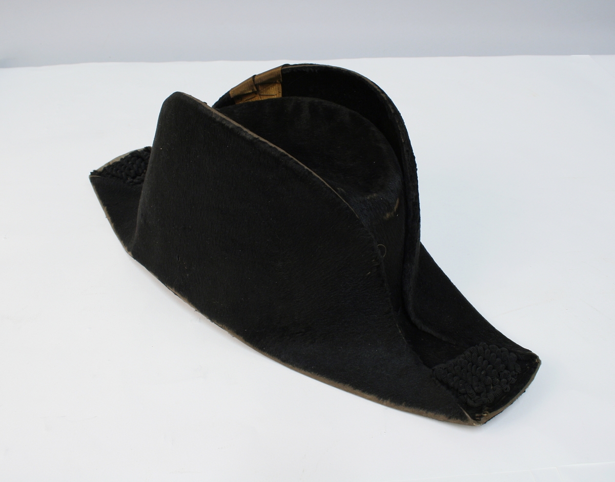 Hatten har nasjonalkokarde, krampe og besetning av possementsarbeid i gull.