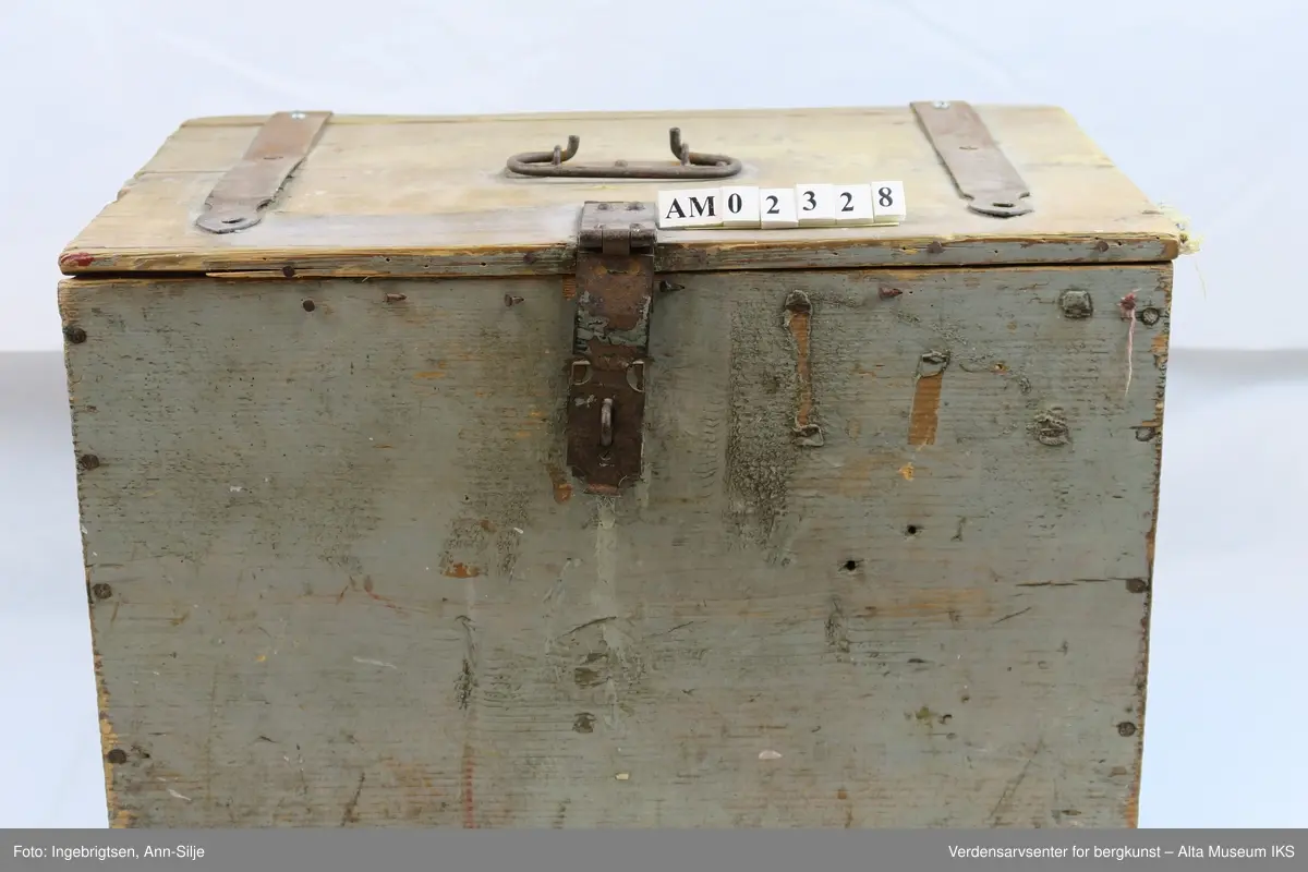 Teknikk: Spikret sammen av 11 1/2" ulimte bord slik at skrinets høyde, bunn og lokk har samme dimensjon ( 11 1/2"= 29,5 cm.)
Form: Rektangulær kasse med hengsler, låsbeslag og håndtak av jern.
En god del av malingen på kassen er flaket av.