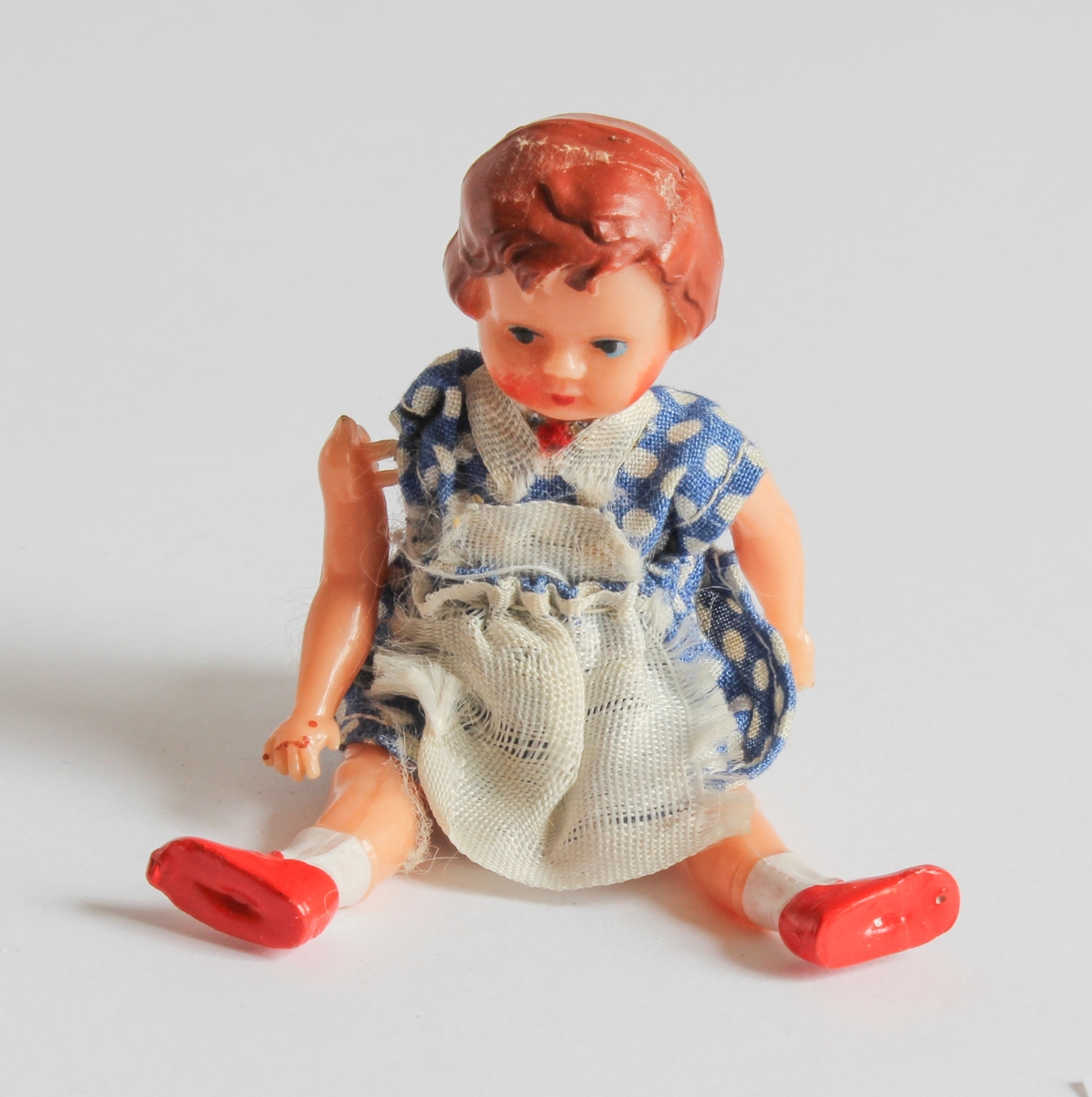 Gitt av Gerd Berit Lie
Hjemmelaget dukkehus av pappeske med to rom. Tapesert, Laget av far, Lorentz Lie (f.1908). Ulike møbler og dukker hører til med til huset. Totalt 35 deler. Det er egen spisestue i tre, bestående av 9 deler (spisebord, stoler, veggur, bokhylle, skap). Det er bad bestående av 3 deler (badekar, servant og toalett i turkis plast). Tilsammen 8 dukker i miniatyr størrelse. Egen kjøkken del med 6 ulike deler (kjeler, kjøkkenbord, fjøler, vase). Og 8 små plastskjeer med skuff.