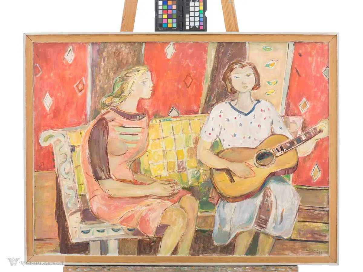 To kvinner sitter på en gul benk mot en rødlig bakgrunn. Den ene kvinnen har et lyseblått skjørt og en lys bluse, og holder en gitar. Den andre kvinnen sitter ved siden av i en lys rød kjole med hendene foldet  i fanget, og det ser ut som om hun synger.