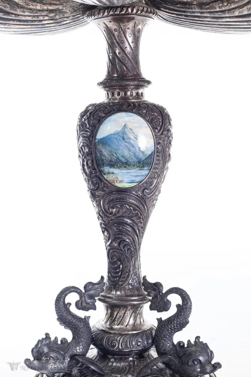To emaljerte medaljonger: Byvåpen og Romsdalshorn.