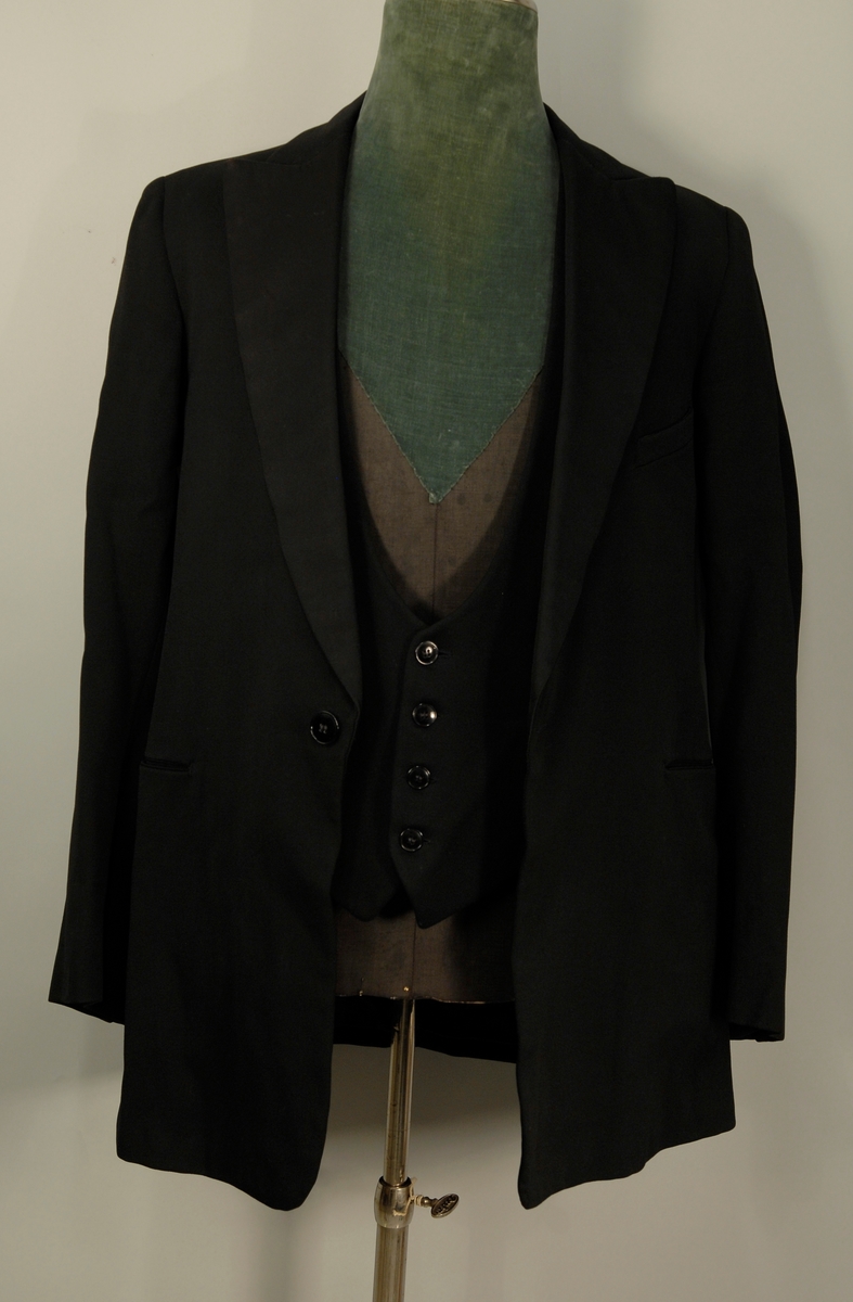 A: Jakke
Dyp V-formet halsskjæring, enkeltspent med ein knapp og knapphull. Spisse slag, kledd med diagonalvevd svart natursilke. Brystlomme og stikklomme i hoftehøgde i kvar side. Tosømserme med tre knapper. For av satengsvevd mercerisert bomull.

B: Bukse
Stikklomme øvert i kvar sidesøm og øverst i kvar sidesøm og øverts på høgre bakstykke. Gylf med skjult lukkning med tre knapper og knapphull. Splitt midt bak, liten trekantet innskjøtning, spensel med spenne. Linning 2 cm høg bak, 3,5 cm foran og lukkes med hekte. Seks blålige metallknapper for bukseseler i linningen som er foret med med kvitt satengvevd bomullstøy med trykte småfigurer.

C: Vest
Dyp. U-formet halsskjæring, enkeltspent med fire knapper og knappehull. Forstykkene avsluttes i spisser. Skråstilt stikklomme på v. forstykke, tilsvarende i livhøgde på kvart forstykke. Rygg av samme tøy som for i jakke. Splitt midt bak og i sidene. Spensel med spenne. Fór av samme tøy som bukse.