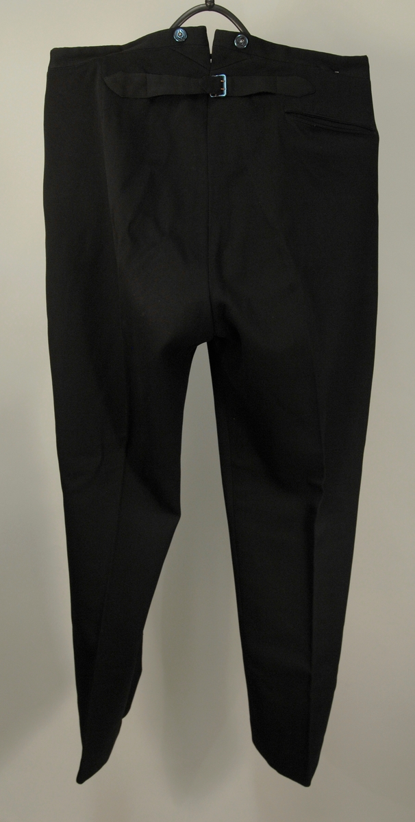 A: Jakke
Dyp V-formet halsskjæring, enkeltspent med ein knapp og knapphull. Spisse slag, kledd med diagonalvevd svart natursilke. Brystlomme og stikklomme i hoftehøgde i kvar side. Tosømserme med tre knapper. For av satengsvevd mercerisert bomull.

B: Bukse
Stikklomme øvert i kvar sidesøm og øverst i kvar sidesøm og øverts på høgre bakstykke. Gylf med skjult lukkning med tre knapper og knapphull. Splitt midt bak, liten trekantet innskjøtning, spensel med spenne. Linning 2 cm høg bak, 3,5 cm foran og lukkes med hekte. Seks blålige metallknapper for bukseseler i linningen som er foret med med kvitt satengvevd bomullstøy med trykte småfigurer.

C: Vest
Dyp. U-formet halsskjæring, enkeltspent med fire knapper og knappehull. Forstykkene avsluttes i spisser. Skråstilt stikklomme på v. forstykke, tilsvarende i livhøgde på kvart forstykke. Rygg av samme tøy som for i jakke. Splitt midt bak og i sidene. Spensel med spenne. Fór av samme tøy som bukse.