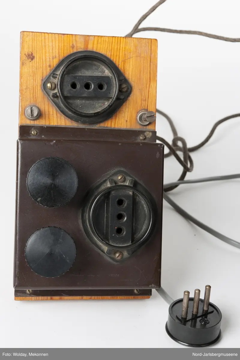 Brun metallkasse med lufterister på høyre kortside og topp. front med reguleringsknapper og hjul, rød lampe, og uttak. Elevapparater har to reguleringshjul og er montert på treplater som er koblet sammen med forsterkeren med ledning og kontakt, og til øretelefonene med ledning i kontakt. Øretelefonene er av bakelitt, metall og lær.
Sort bakelitt også på elevapparatene.


5 deler tilsammen