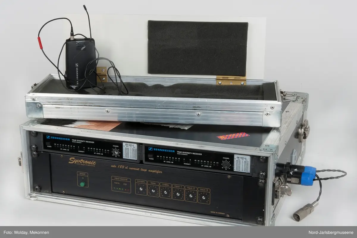 Spesialbygget metallkoffert for audiomåleapparater. Kofferten har åpning på hver ende. På den ene siden finner man måleinstrumenter; to "True Diversity Receiver" og en stor forsterker. I lokket på denne siden er det plass til å oppbevare mindre tilleggsutstyr. Under det andre lokket finner men baksiden av apparatene samt ledninger. Lokket her også plass til ekstra, lange ledninger for kobling til andre apparater. På dene ene langsiden er det tre uttak for koblinger, hvorav en har koblingsledning i.