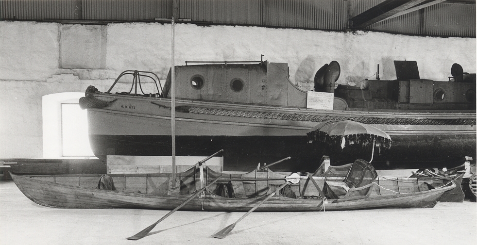 A Thames skiff is a traditional River Thames wooden rowing boat used for skiffing. These boats evolved from Thames wherries in the Victorian era to meet a passion for river exploration and leisure outings on the water. 
This boat was probably built prior to 1893. It came with a rya rug, three pairs of oars, an umbrella, two cushions, a mast and a combined boat hook and paddle. 
It was brought to Sweden by Albert Isaksson, who was the Swedish representative of Lloyd's.
The boat was later bought by Sven Abrahamsson and Börjessons boatyard on Rindö in the Stockholm archipelago. In 1931, it was sold to Ragnar Vinberg on Blidö.
