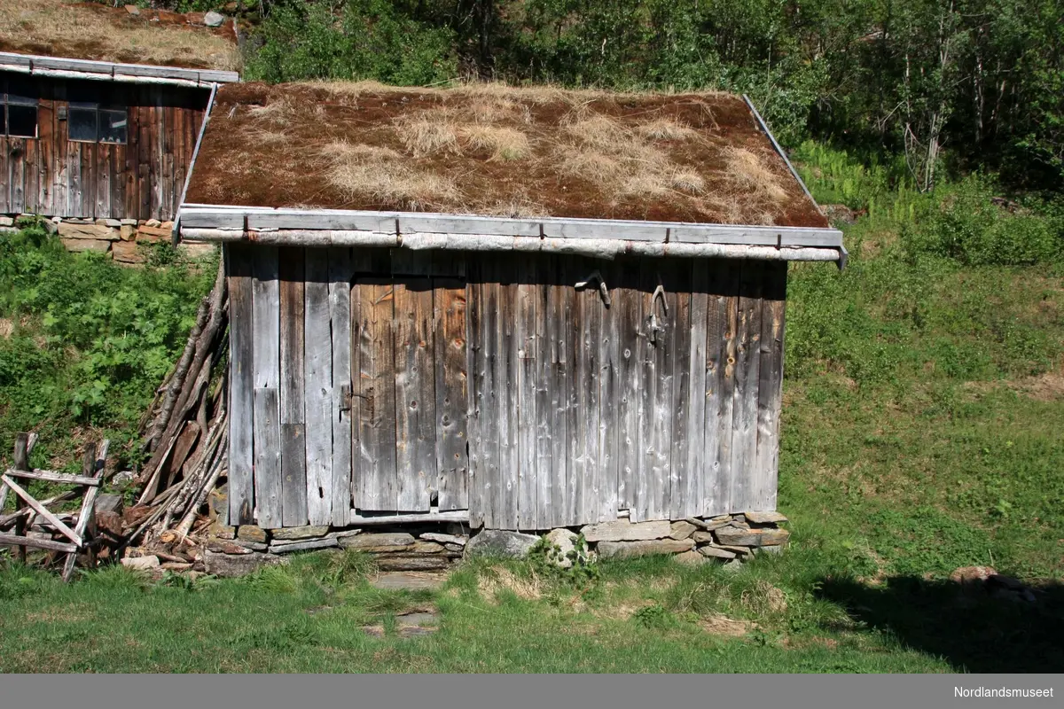 Vedskjulet er bygd av stolper og forskjellige slags bord. På sørveggen er det brukt båtbord som materiale.
Drenering: Naturlig – grøft gravd på baksida.
Fundament: Natursteinsmur og syllsteiner.
Bærende konstruksjon: Stavbygd.
Yttervegger: Rettkantbord, delvis som smit` (følger treets naturlige bredde). Kledning saget på kransag (handsag). Gjenbrukte båtbord på sørvegg.
Dør: Enkel labankdør.
Tak: Bærende konstruksjon kombinert sperrer med beter/samhald. Materialer av lauvtre.
Taktekke: Tekke av plast og torv.