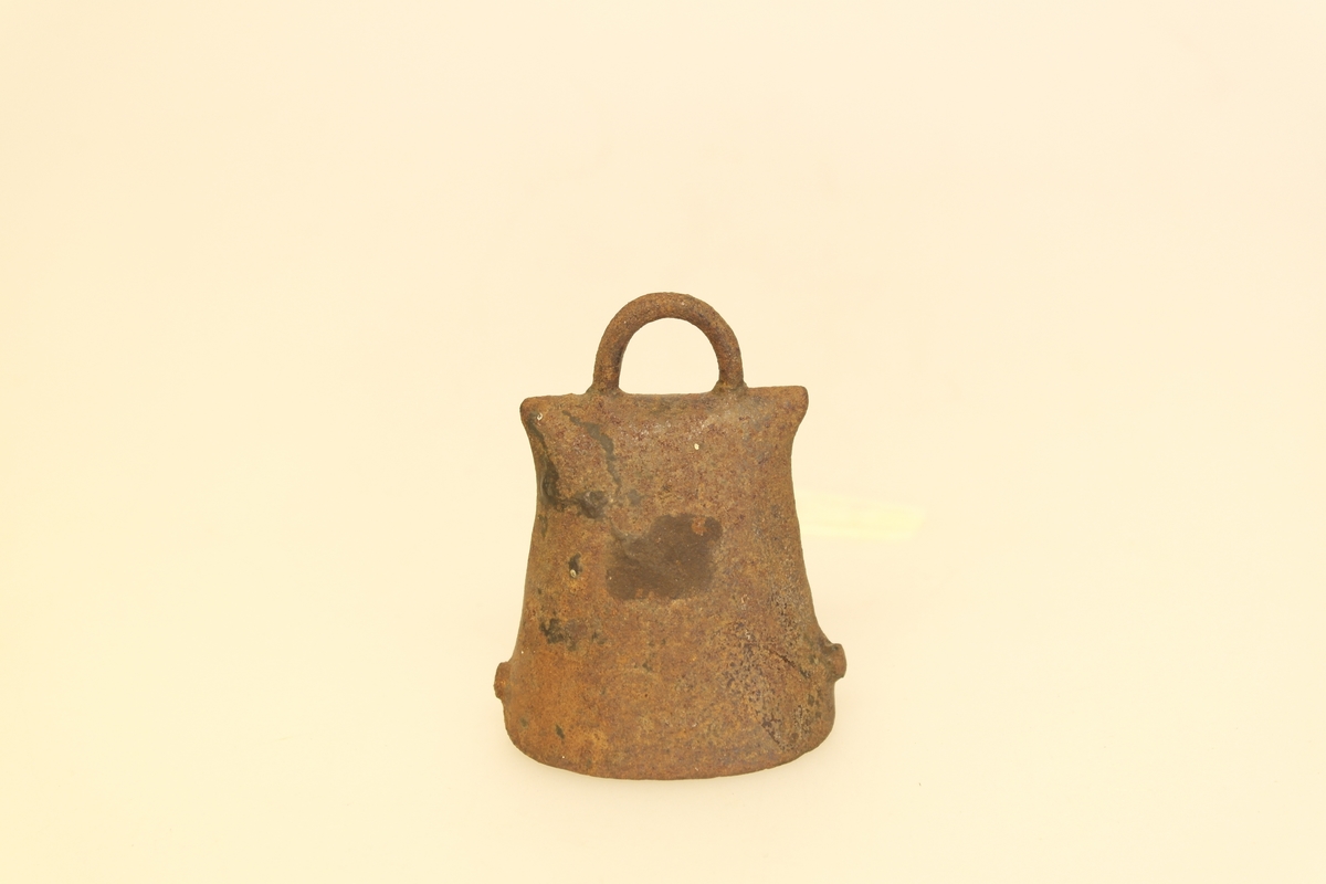 Sauebjelle i hamret og loddet kobber. Hamret til av et flatt rektangulært  stykke. Naglet og loddet sammen i siden. Kolv/dingle er festet til hempe inne i bjella. Hempe oppe på bjella.