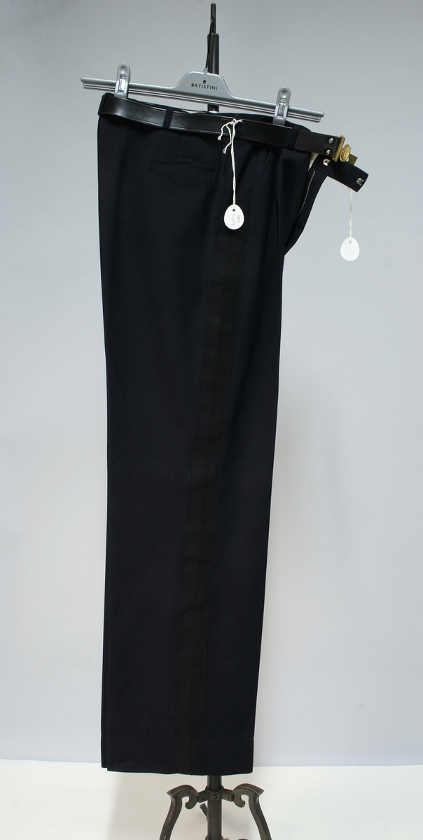 Uniform for politinspektør etter 1963-reglement med merking etter 1977-reglement. Helårsuniform M/1963 med skjorte, langbukse, belte, helårskappe og jakke. Skyggelue med gullbrodert bånd, loslue og båtlue M/1967. Kappen og jakken har skulderklaffer av flettede gullsnorer med to sølvstjerner og festeknapp i gullbroderi. Skjorten har en enklere skulderklaff med to gule render og to sølvstjerner. Det følger med et ekstra enkelt lærbelte og et ekstra sett skulderklaffer til skjorte. Plaggene har gullfargede løveknapper.