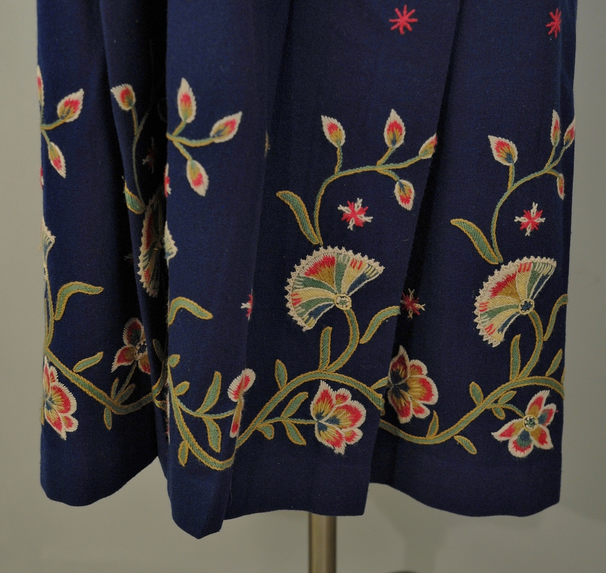 A: Bunad. Blått ullstoff, tynn klede. Har ein brodert bord 5 cm frå nedre kant. Brodert i ullgarn. Borden er 33 cm bred og går rundt same høgde. Det er en grenbord med blomster sydd i plattsøm, kontursting og franske knuter. Overdelen er eit skjørteliv. Rundt skjørtet er det brodert ein bord i kvit snorsøm, fiskebeinsting og franske knuter. Bak 3 stjerner i røde og kvite, foran på skjøtene 4 stjerner. Den broderte kvite borden fortsetter foran og opp og rundt halslinning. Foret overdel med lysgrå silke. 8 sølvringer foran i åpningen for sølvkjede. Denne bunaden har nedsydde folder frå 5 cm og opp til 8,5 cm lengde (ikkje vanleg). Splitten i skjørtet er satt saman med to trykknapper og ein hekte, og overdelen er satt saman i livet med to hekter. Skjørtet er festet til overdelen ti steder. Overdelen går i spiss ned bak.

B: Lue
Maken stoff og broderi som bunad. På pullen er det brodert eit tre med blomster. Same broderi som på overdel er brodert foran på luen. Foret med lysegrå silke. Kyse fasong. H: 17,5 cm, B:18,8 sm

C: Veske
Same stoff og broderi som bunad. Lås i messing. Same for. Låsen påsydd for hand. Låsen er merket: 
JONS KRISTIANSEN
KJOSE
NN
Veske med lås, total lengde: 28,7 cm, bredde: 16,4 cm

D: Skjorte
Kvit bomull med nuppereller. Halslinning 6 cm x 36 cm, skjorta rynket rundt halslinning. Splitt 16 cm ned midt foran. Lengde, 42 cm. Innsatt spjeld under arm 7cm x 7 cm. Vidde arm 42 cm, armlinning 6 cm x 19,5 cm. Total bredde frå arm til arm 153 cm, hvorav bolen er 52,5 cm. Innfelt skulderstykke 8,3 x 15,6 cm. Knapphull for knapper.