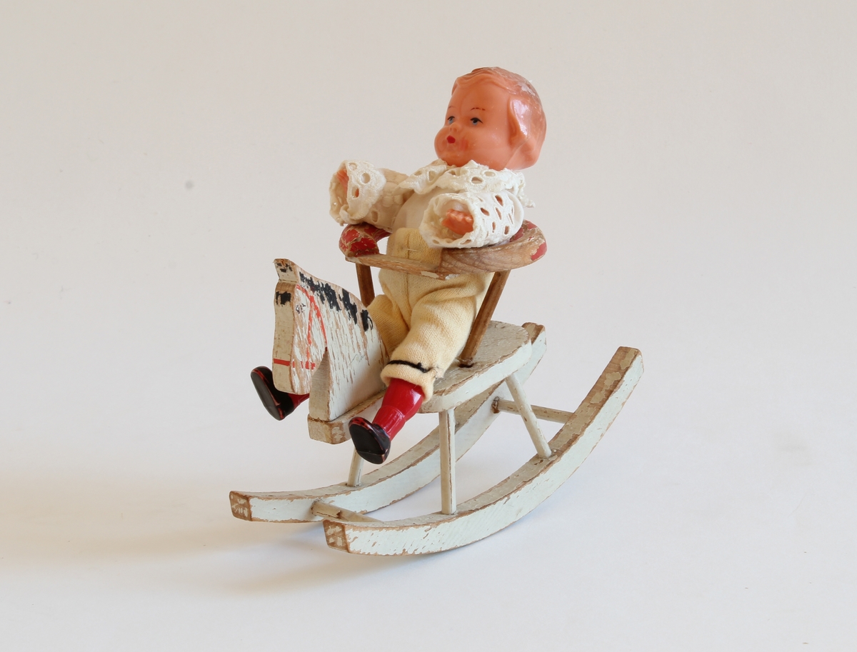 Siste eier Elisabeth Marthinsen. Gitt etter ønske fra Elisabeth til Kvinnemuseet etter hennes bortgang. Giver: datter, Heidi Graff.

Dukken er en veldig liten guttedukke som sitter på en liten gynghest. Gyngehesten er av tre. Guttedukken sitter i en stol på hesten. Stolen kan tas av fra hesten. Guttedukken er kledd i blonde skjorte og hvite nikkers med røde strømper. Hesten er hvit. Det står ikke oppført fra giver/eier om hvor Elisabeth fant denne dukken eller når hun kjøpte den.  Dukken/dukkene betydde svært mye for Elisabeth.  Se historien under.

Da Elisabeth var 13 år og bodde i Bodø, ble hun tatt med "på ferie" til Oslo. Mor, far, bror, søster og Elisabeth reiste fra hjemmet. Elisabeth tok ikke med noen leker og fikk ikke sagt farvel til noen - hverken familie eller venner. Hun fikk senere vite at " på ferie" betydde at de hadde flyttet. 

Som voksen ble det viktig for henne å få tilbake de dukkene og lekene hun hadde hatt som barn. Dette utviklet seg til å bli en hobby. Hun reiste rundt med ei venninne på markeder, antikkmesser og auksjoner. Dette koste Elisabeth seg veldig med.  

Elisabeth flyttet til Kongsvinger i 1973, siden foreldrene hennes hadde flyttet hit. Hun var først husmor. Pendlet noen år til Oslo, og arbeidet så videre noen år  i Kongsvinger.