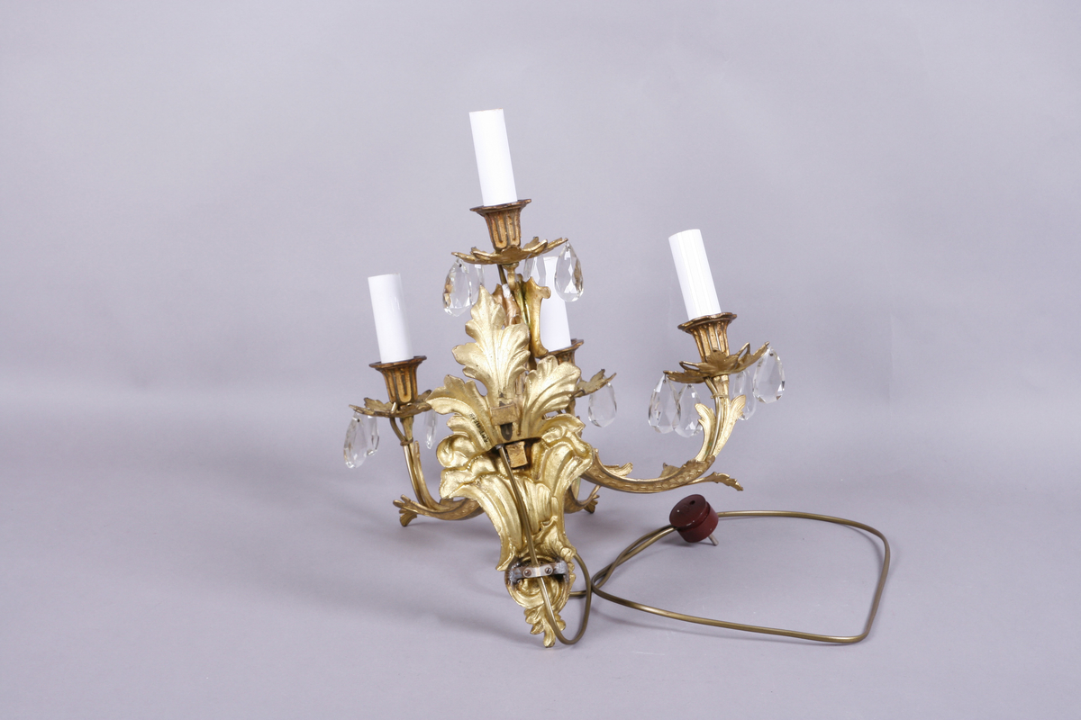 Elektrisk vegglampe med tre armer. Støpt metall. Forgyllet. Påhengte fasetterte glassdråper.