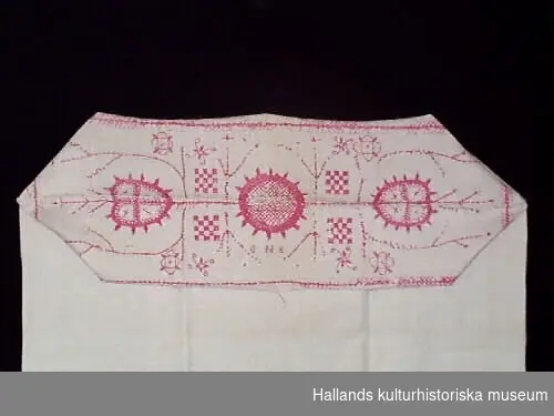 Putevar av vitt linne. Hallandssöm broderat med rött lingarn i geometriskt mönster.