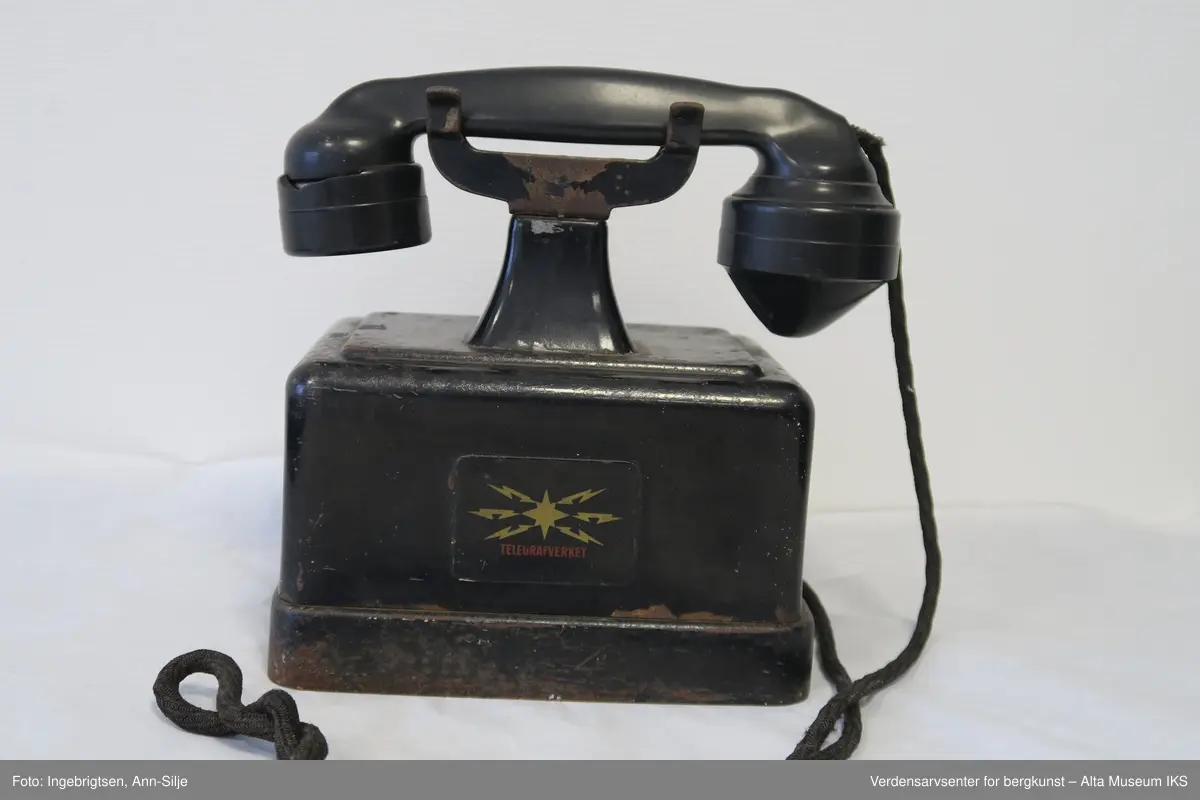 Prismeformet boks med bæreklo på toppen og telefonrør.