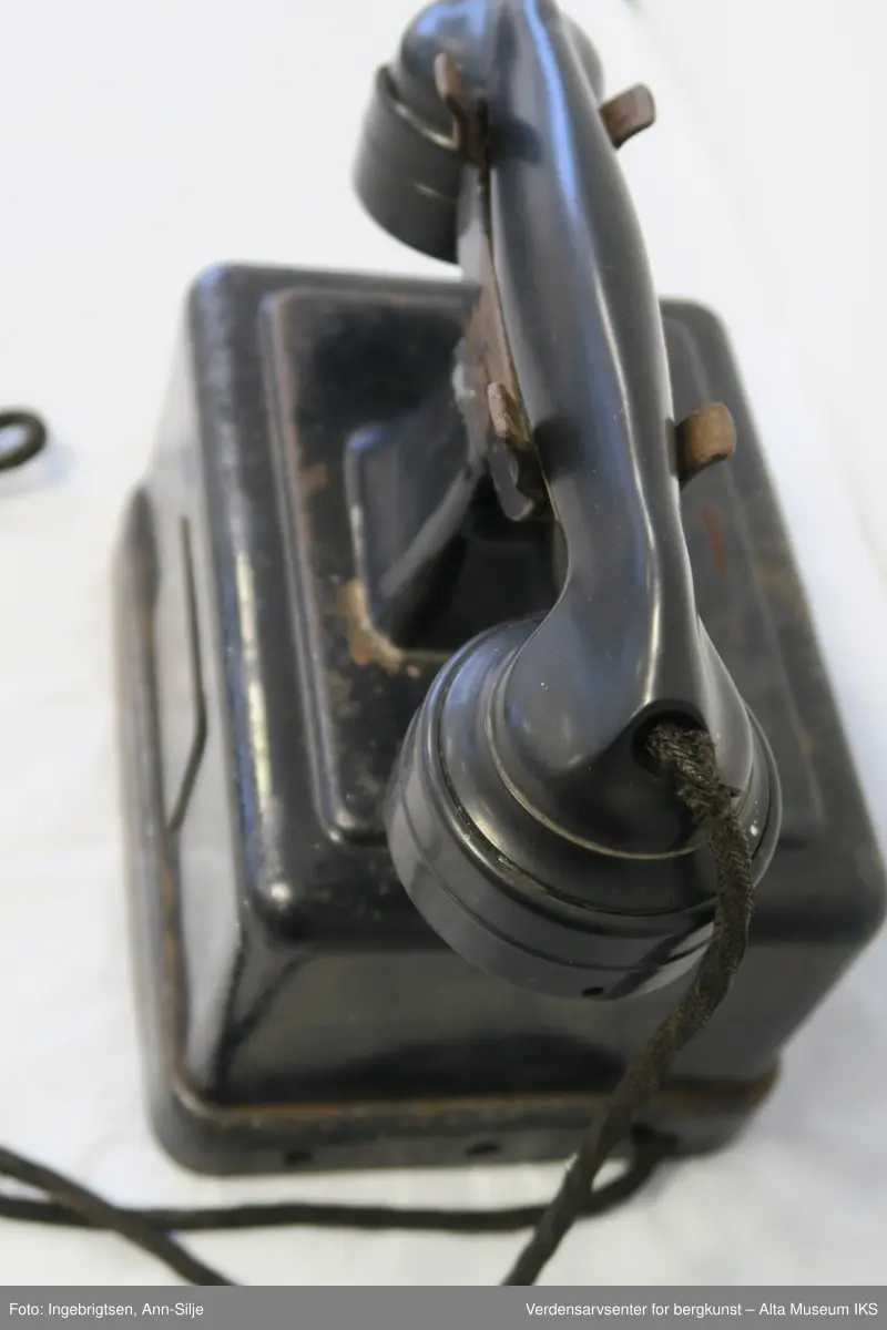 Prismeformet boks med bæreklo på toppen og telefonrør.