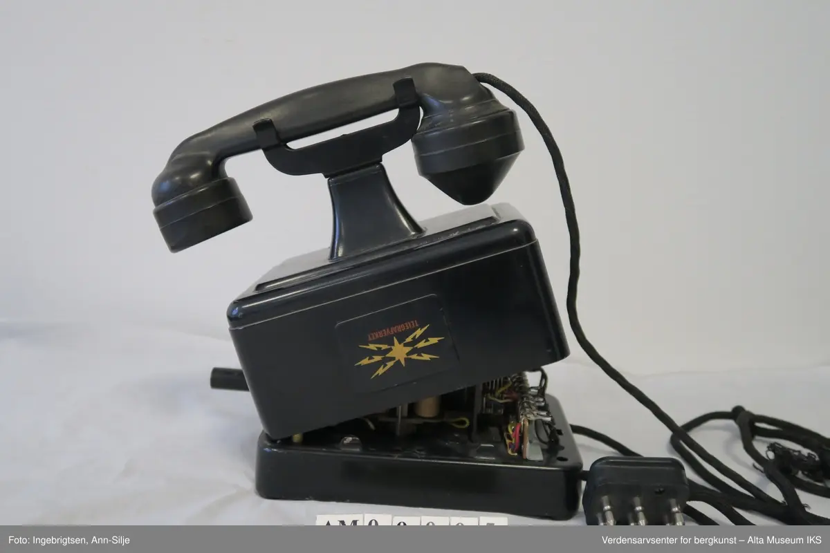 Prismeformet med bæreklo på toppen og telefonrør. Emblem med logoen til Telegrafverket på framsiden av boksen. Boksen er åpnet fra bunnen og er kilt fast slik at det ikke er mulig å lukke den. På baksiden av boksen er det et klistremerke med motiv av Langbein.