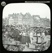 Amsterdam - the Vegetable Market. Bilden visar en ekonomisk kommers och rörelse, med en kanalbro och Amsterdams karakteristiska hus i bakgrunden.
Ur serien 