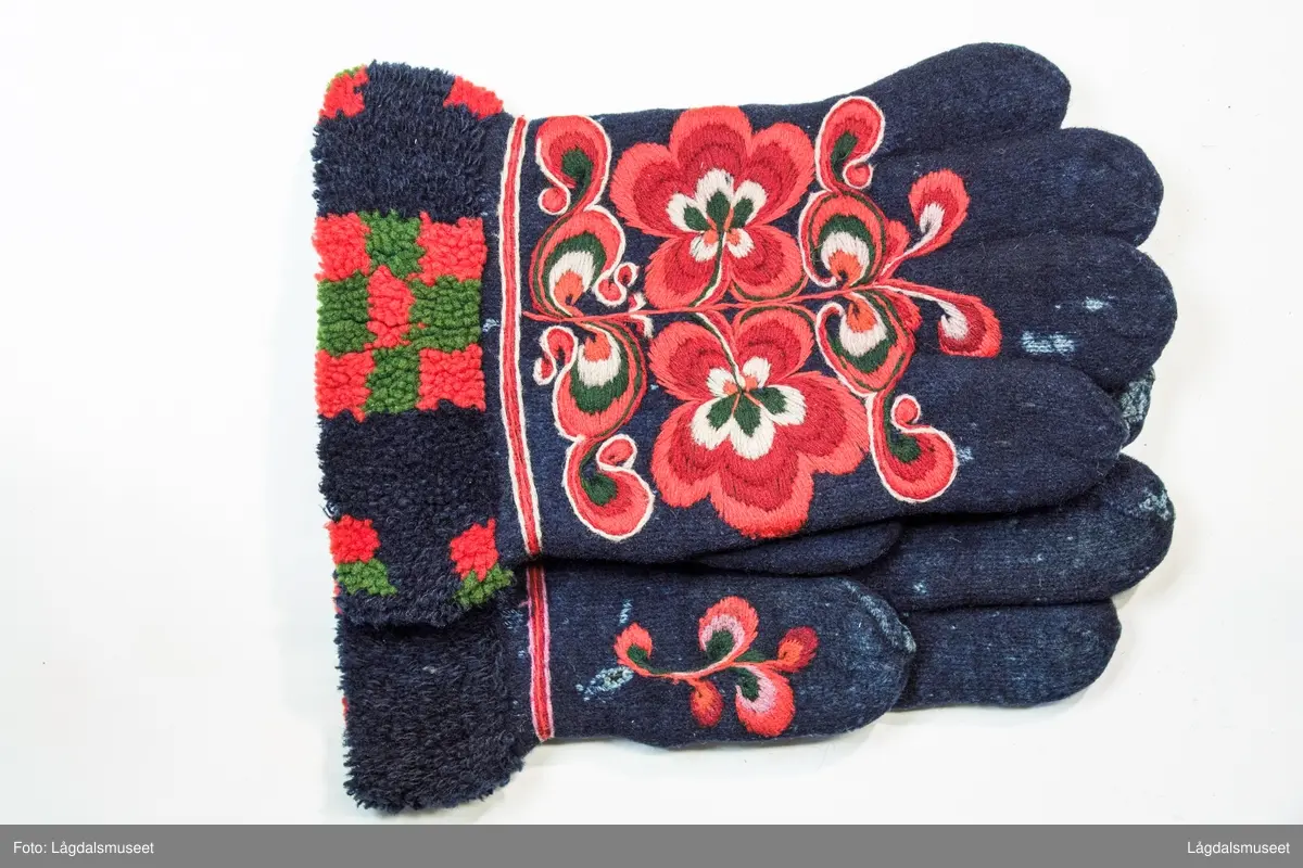 Broderte blomster og motiver på forsiden og tommelen i plattsøm. På håndbaken er det korsstingsbroderte initialer.