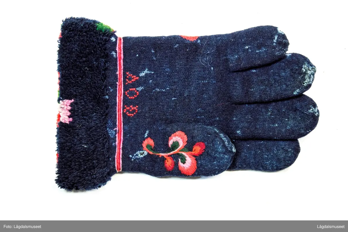 Broderte blomster og motiver på forsiden og tommelen i plattsøm. På håndbaken er det korsstingsbroderte initialer.