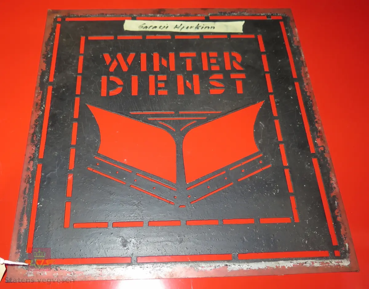 Sjablong/mal av plastlignende stoff, kanskje celluloid. Motivet viser en snøplog og teksten er "WINTER DIENST".
