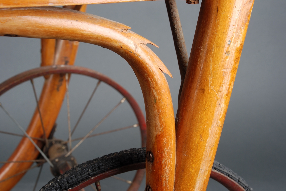 Rullestol i formpresset tre. Fotplate. Håndtak i forlengelsen av ryggen. Rotting rygg. Finert sete erstatter rotting. 2 hjul.