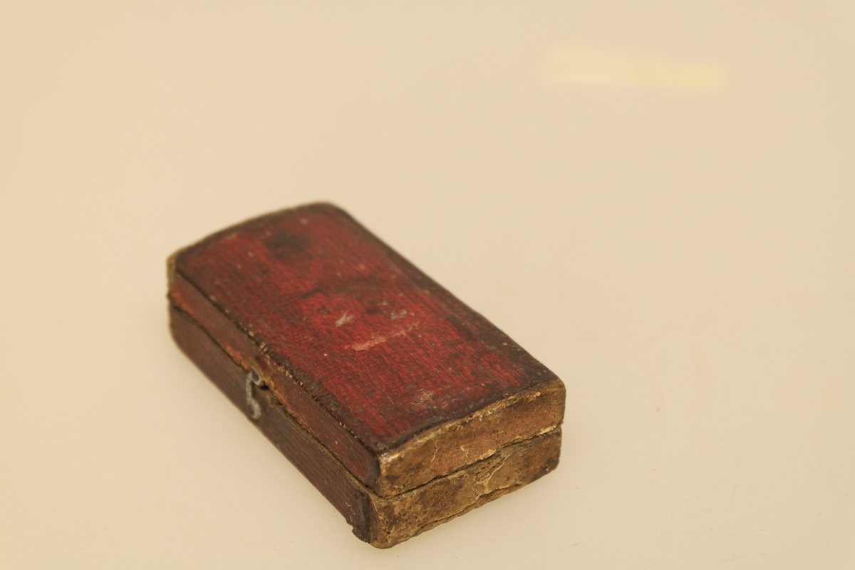 Sneppert (a) med eske (b) til bruk ved årelating. 
A) Smidd jernblad og messing. Innrissing av initialer.
B) Eske av tynt tre trukket med rødt papir utenpå og brun velour inni. Lukkes med en messinghempe.