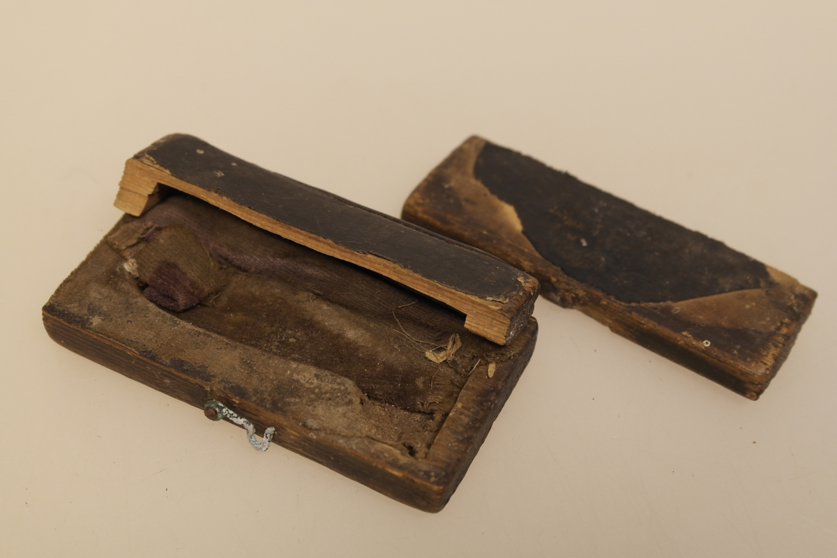 Sneppert (a) med eske (b) til bruk ved årelating. 
A) Messingsneppert med jernblad.
B) Eske i skåret og pusset furu. Trukket med svart lær utenpå og velour inni. Lukkes med en messinghempe. Skåret initialer i bunnen.