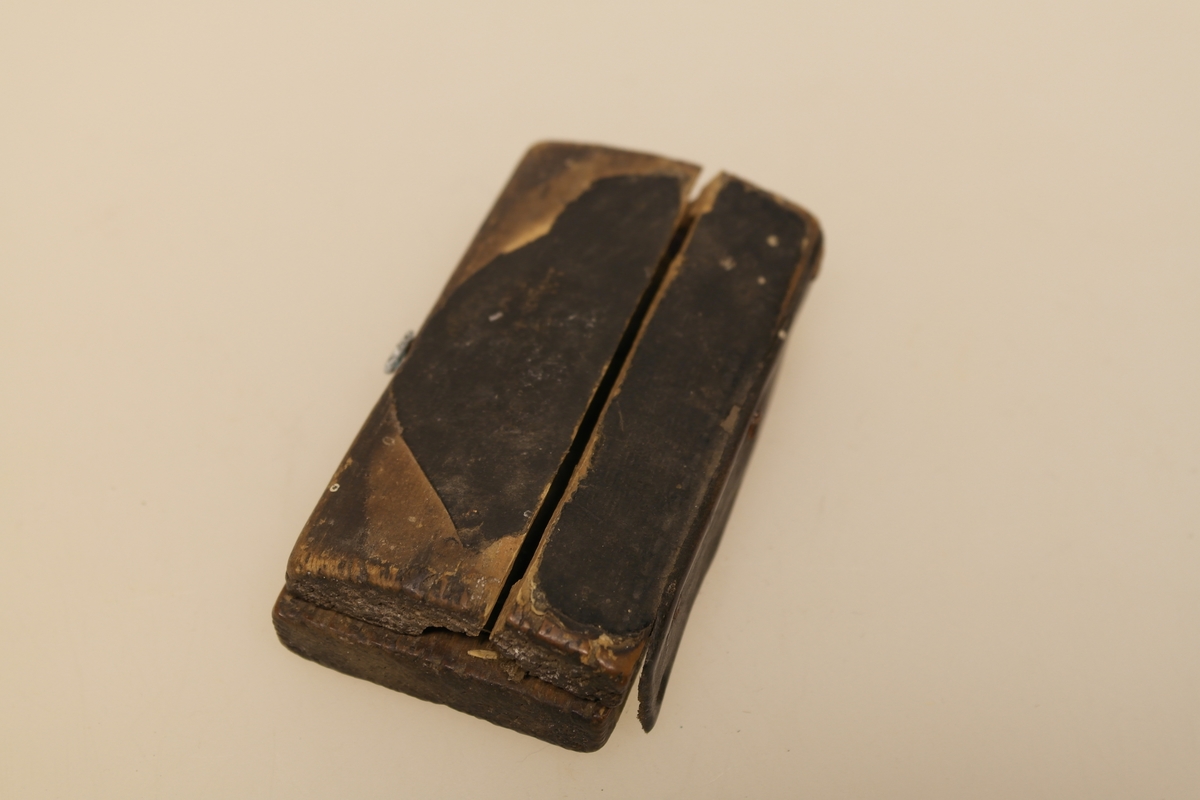 Sneppert (a) med eske (b) til bruk ved årelating. 
A) Messingsneppert med jernblad.
B) Eske i skåret og pusset furu. Trukket med svart lær utenpå og velour inni. Lukkes med en messinghempe. Skåret initialer i bunnen.