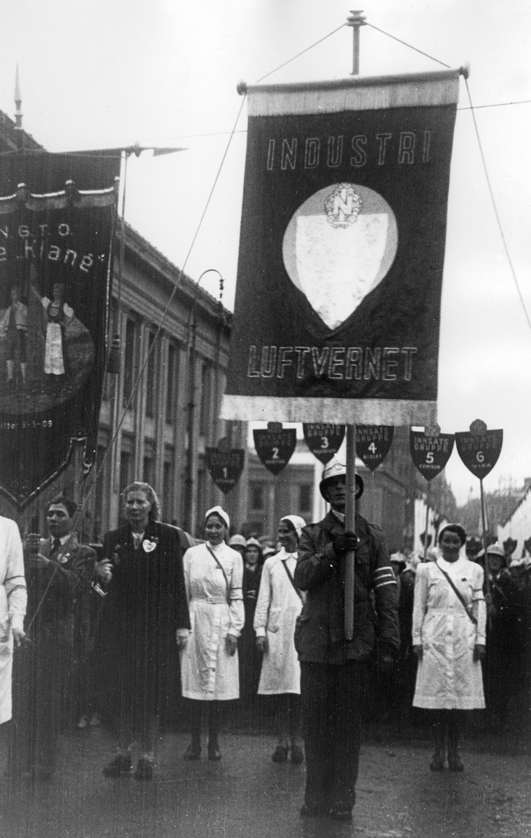 Fra Oslo under fredsdagene i 1945. Industri Luftvernet med fane i tog oppover Karl Johans gate.