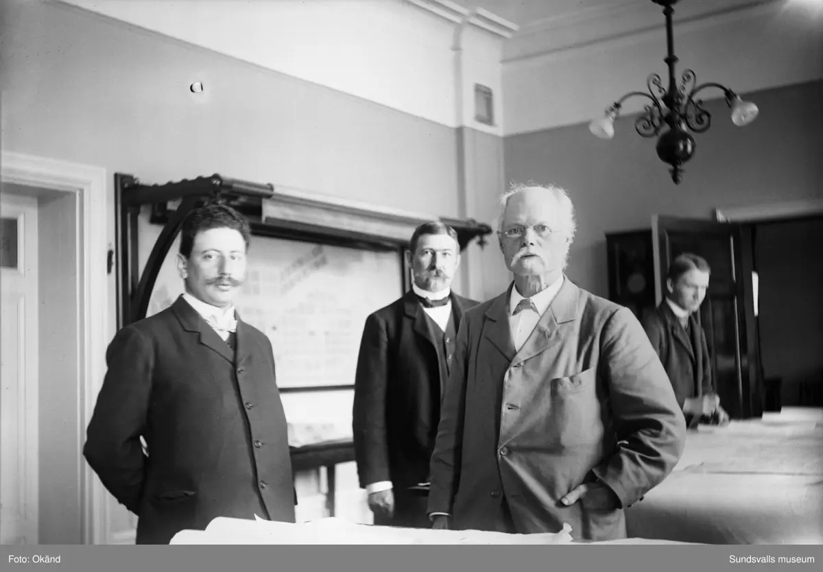 Från vänster stadsingenjör Karl Abersten, stadsarkitekt Nathanael Källander och bokhållare J R M Ringius. Mannen i bakgrunden är okänd. Bild nr 2 är tagen på samma kontor med okänd man sittande vid bord.