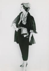 Modell i jacka, silkessjal, kjol, hatt, armband och högklack