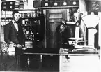 Första Konsumbutiken i Hedesunda före 1920.
Interiör från Konsums första butik i Ås.
På bilden väger Erik Wiklund något matnyttigt och till vänster står Conrad Sörling. Erik Wiklund blev senare föreståndare efter sin far.