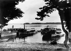 Flottare i Östveda.
Flottare med båtar i Östveda 1911.
Båtarna Snappop och Måns användes vid samling av drivvirke. Domnarvet drog timmerbommarna över Bramsöfjärden. Mitt i bilden syns fören på en träpråm.