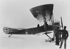 Flygplan Albatros nr 6 med skidor står på Storsjöns is, 1915. Flygförare Carl Silow och flygspanare på plats i flygplanet. Flygmekaniker bredvid flygplanet. Vy från sidan.