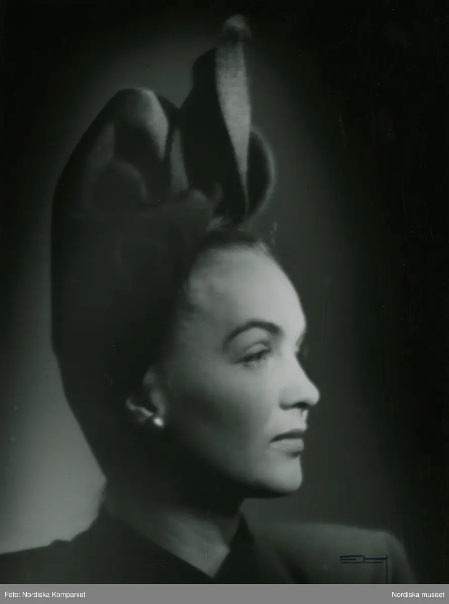 "Pavy, Paris". mode för Nordiska kompaniet 1945. Modellen Hjördis Genberg Nivén i hatt, hög modell, daperarad, utan brätte, platt nacke.