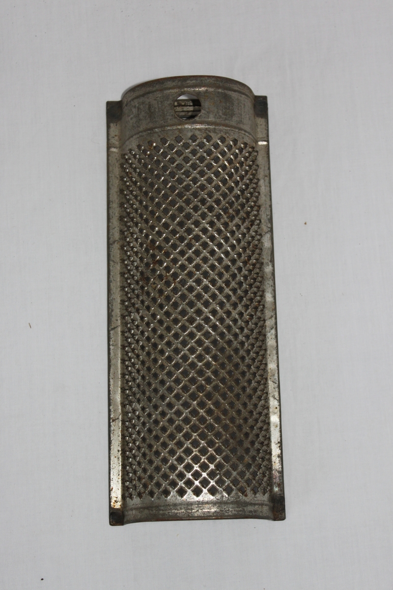 Rektangulärt rivjärn av förzinkad järnplåt, i kupad form som hålls samman av järnband på baksidan. Rivyta med relativt grova hål, slagna med fyrkantigt don. Hål för upphängning i överkanten.