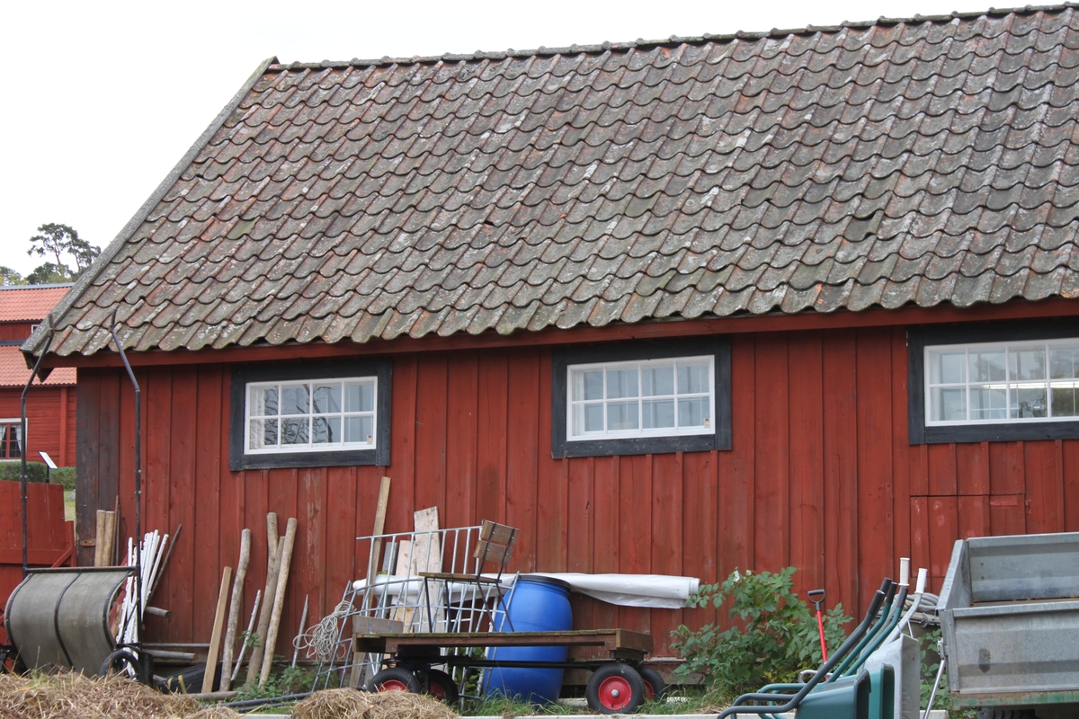 Byggnaden är uppförd i stolpverkskonstruktion, på huggna hörnstenar. Grunden täcks av plankor. Yttervägg av locklistpanel. Sadeltak med branta takfall. Undertak av brädor, lagda horisontellt. Takbeklädnad av enkupigt tegel. Vindskivor och vattbrädor i trä. Liggande fönster längs norra långsidan, spröjsade med åtta glasrutor. Lunettfönster på östra gaveln, vindsvåningen. Skärmtak på stolpar utefter södra långsidan, med beklädnad av brädor. Innergolv av cement i hela byggnaden. Innervägg mellan rummen av brädor. Ytterväggarna i rummet klädda med skivor. Taken är av brädor. Hela byggnaden inredd för djurhållning, med boxar, spolplatta, förvaringsutrymmen m m.