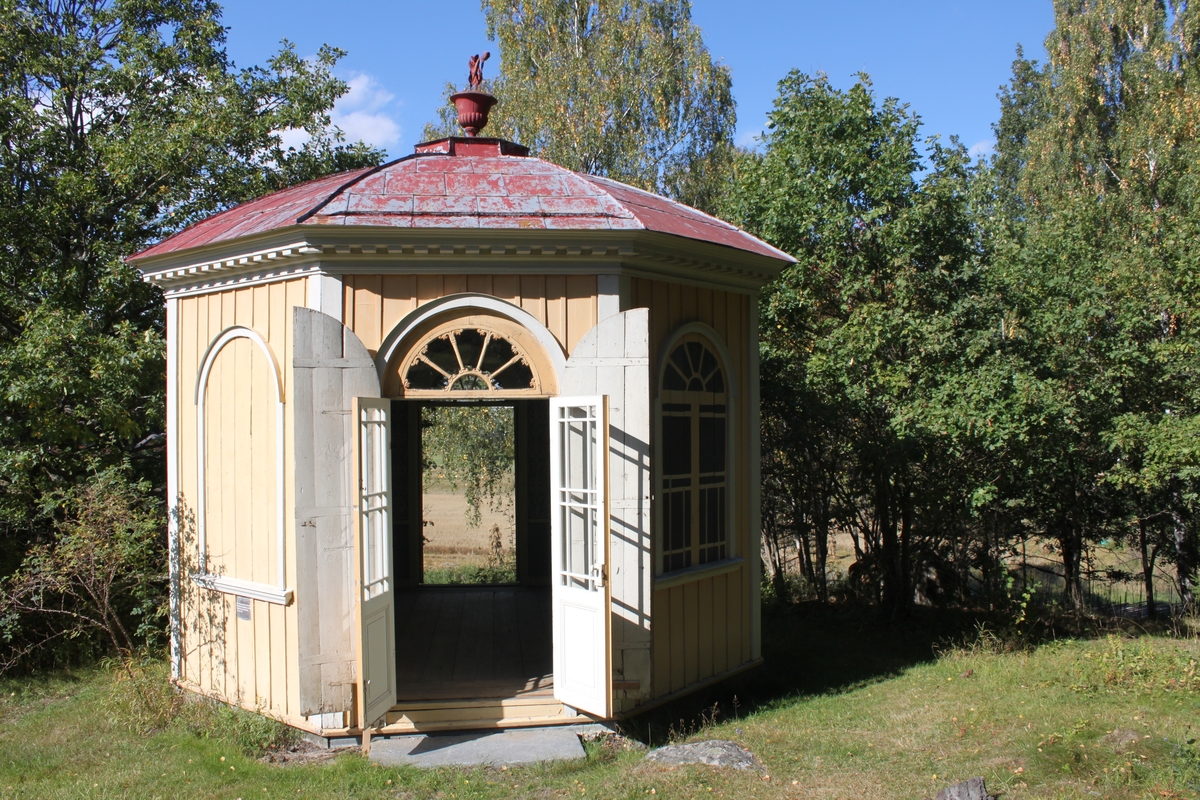 Byggnadsstommen är tillverkad av timmer med släta knutar, dolda bakom ljust gråmålade knutlådor. Lusthuset har ett åttkantigt utförande och är placerat på en syllmur av huggen sten. Byggnaden ligger i svagt sluttande terräng. Den södra entrén har ett trappsteg av huggen sten och den motsatta entrén har två trappsteg. Det åttkantiga kupoltaket är klätt med falsade kvadratiska plåtar och kröns av en blomurna och blombukett i plåt. Plåten är målad i en röd kulör. Takfoten har ett tandsnitt i trä. Fasaden är klädd med locklistpanel och har en dropplist nederst, allt målat i en ljust gul kulör. Dubbla entrédörrar är placerade mitt emot varandra på fasaden. De yttre pardörrarna är tillverkade av plankor och har tre gångjärn - stubbhakar per dörrblad. De inre pardörrarna, som hänger på franska gångjärn med runda tappknoppar, är rektangulara och glasade till 2/3. Rutorna har träspröjsar. Nedtill har dörrarna en fasad spegel. Över innerdörrarna finns ett lunettfönster med skuren träspröjs. De sex  fönsterluckorna är rundade upptill som ytterdörrarna. Fyra av dem är öppningsbara. Underdelen på fönstret har profilerad kant. Innerfönstren är konstruerade på liknande sätt som innerdörrarna, med lunettfönster överst. Överdelen på både dörrar och fönster är plåtkantade i fasaden för avrinningens skull. En dubbeldörr och ett par fönsterluckor är målade i ett mönster som ska ge en illusion av öppna ytterluckor. Detaljer runt fönster, dörrar samt takfot är målade i en ljust grå kulör.


