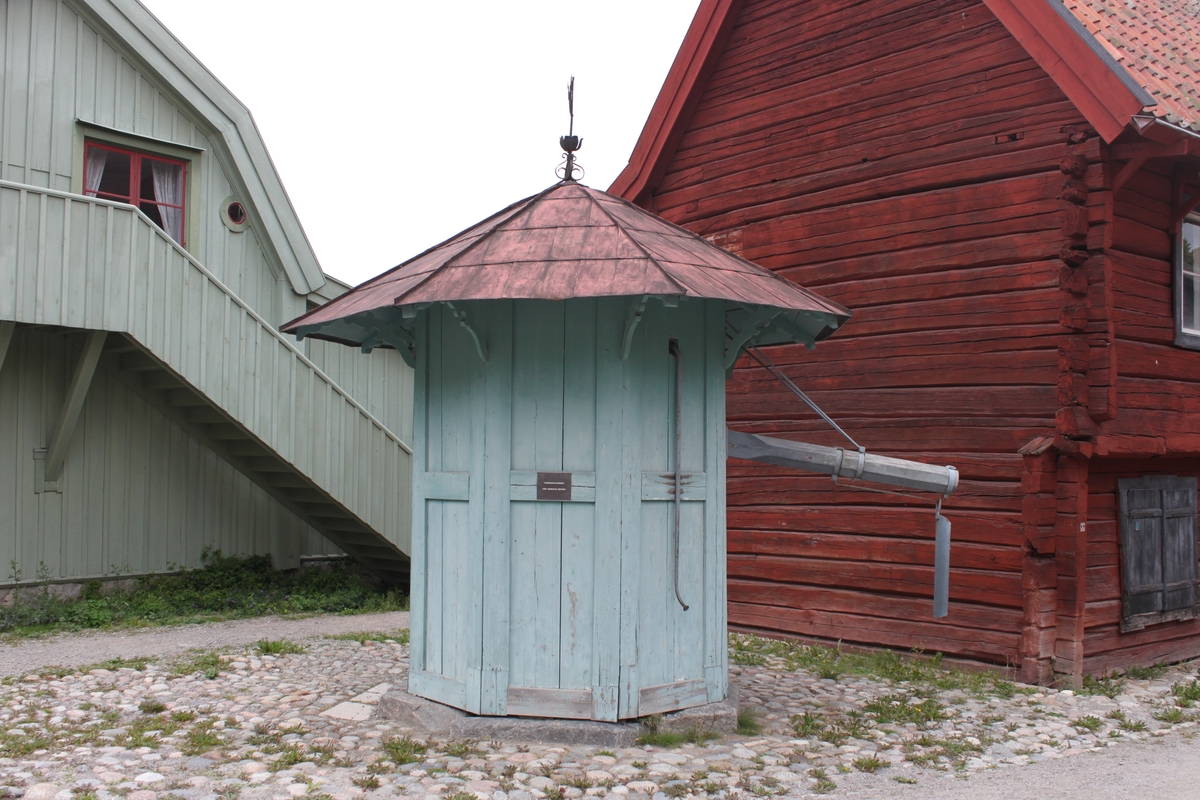 Den åttkantiga byggnaden vilar på en syllmur av huggen sten. Varje sektion består av ett ramverk av plankor och med fyllning av breda plankor, två per ram. En dörr med låshasp och hänglås är placerad i en av sektionerna. Fasaden är målad i en ljust grön kulör. Byggnaden har ett tälttak med åtta takfall. Taksprånget är kraftigt utskjutande, upplyft av konstfullt utsågade konsoler. Takbeläggningen består av kvadratiska, falsade plåtar, målade i en röd kulör. Upptill kröns taket av en drakliknande varelse i plåt. Utskjutande vattenrör i trä, skodd med järn och med vidhängande, rörlig vattenledare. En stång i järn har drivit pumpen. Den är inte funktionsduglig då pumpkomstruktionen saknas.