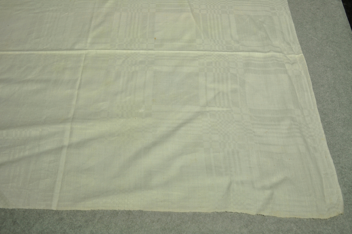 Hvit dreielsduk. Bomullsrenning, lin innslag (halvlin). Duken er sydd sammen på midten og merket S. Opdal. Linet er dyrket og bearbeidet på Opdal. Anne Stine Opdal kom fra Töcksfors og var gift med PetterTorsteinsson. Anne Stine Opdal var mor til Einar Arendt (giver).