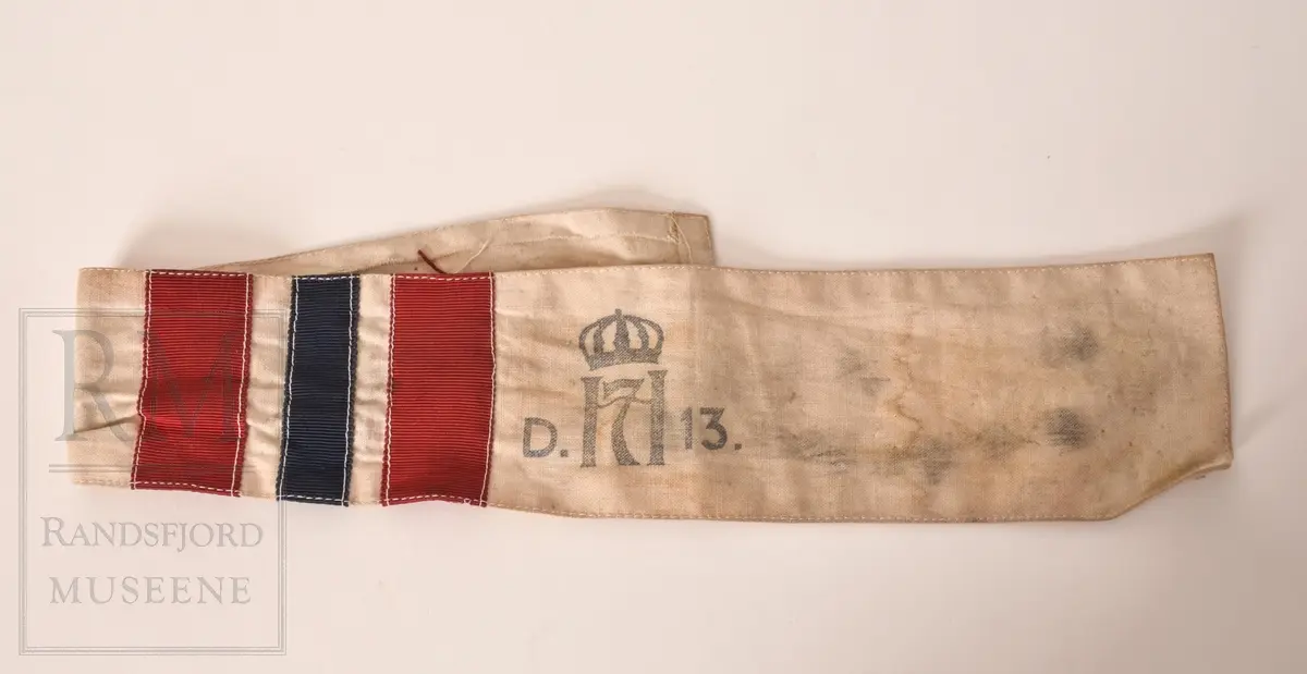 a. Mørk blå kjeledress/ overall med flyvermerke. Militær type. b. Mørk blå lue, berret med H7 luemerke festet og norske farger på bånd. c. Armbind med norske farger. d. Bandolær i lyst brunt lær, messinghemper og spenner. e. Trekantet halstørkle skåret ut av fallskjermstoff (mosegrønn), bit av fallskjermsnor brukt som knyting