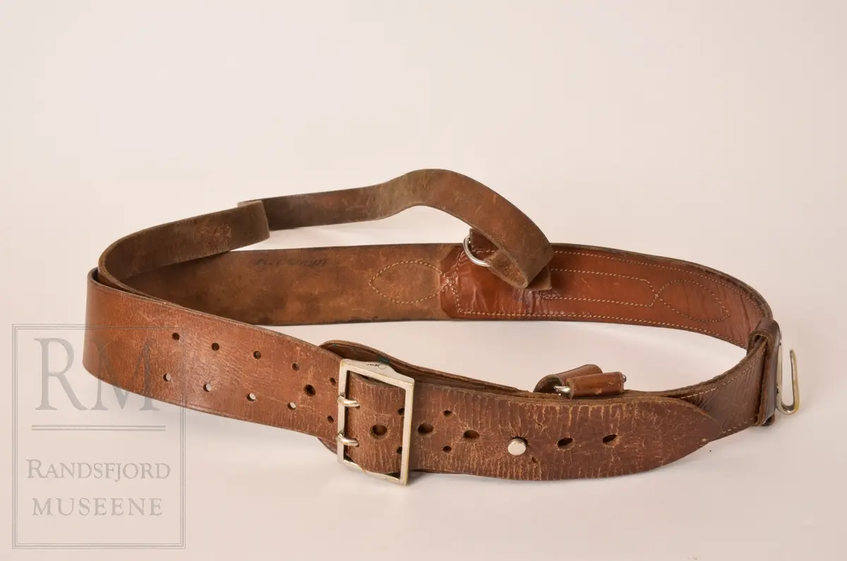 a. Mørk blå kjeledress/ overall med flyvermerke. Militær type. b. Mørk blå lue, berret med H7 luemerke festet og norske farger på bånd. c. Armbind med norske farger. d. Bandolær i lyst brunt lær, messinghemper og spenner. e. Trekantet halstørkle skåret ut av fallskjermstoff (mosegrønn), bit av fallskjermsnor brukt som knyting
