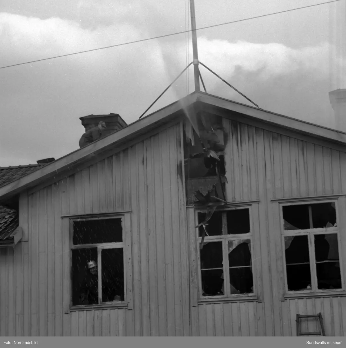 En stor serie bilder från en eldsvåda i kontorsbyggnaden och Bylanders Café vid Luckstaverken, Lucksta ångsåg. Släckningsarbete pågår och massor av människor hjälps åt att rädda så mycket lösöre som möjligt. Elden startade i på övervåningen i kassören Sven Perssons bostadslägenhet. Persson räddade sig ut genom att hoppa från balkongen på baksidan. Brandkårerna från Attmar, Tuna och Sundsvall lyckades till slut få bukt med elden men övervåningen totalskadades och det kafé som fanns inrymt i bottenvåningen fick stora brand- och vattenskador.