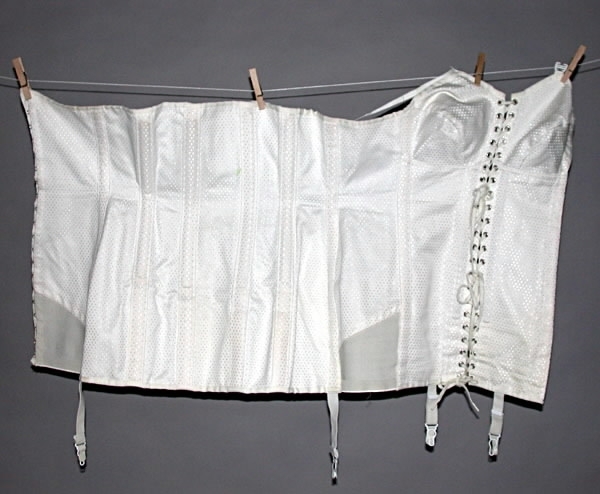 Korsett med snörning framtill. Fyra strumpeband. Material: Textil, ull, bomull, syntetmaterial.