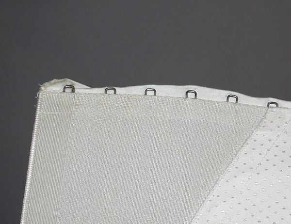 Korsett med snörning framtill. Fyra strumpeband. Material: Textil, ull, bomull, syntetmaterial.